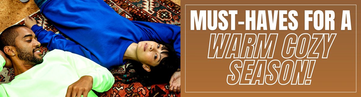 Banner for A male wearing a light green sweatshirt and a female wearing a blue sweatshirt lying on a carpet with text Must-Haves for a Warm Cozy Season